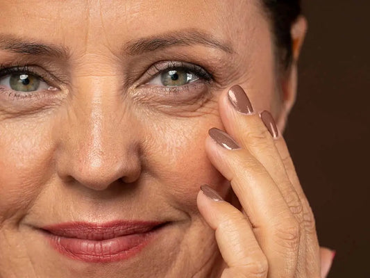 Mature woman gently touching visible fine lines and wrinkles around her eyes